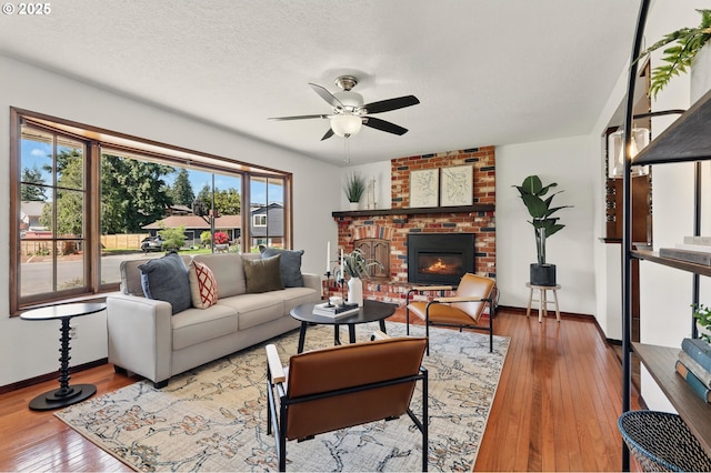 18735 NE Wasco Ct, Portland, OR 97230 - living room with a ceiling fan, hardwood / wood-style flooring, baseboards, a brick fireplace, and a textured ceiling