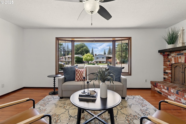 18735 NE Wasco Ct, Portland, OR 97230 - living room with a ceiling fan, baseboards, wood finished floors, a fireplace, and a textured ceiling