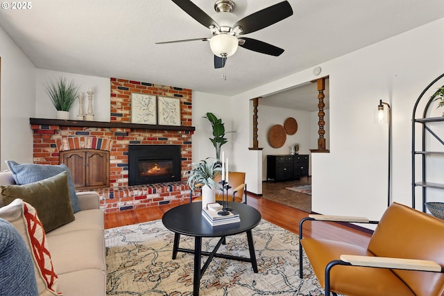 18735 NE Wasco Ct, Portland, OR 97230 - living room featuring a brick fireplace, ceiling fan, wood finished floors, and baseboards