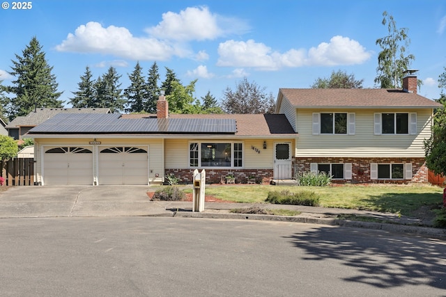 18735 NE Wasco Ct, Portland, OR 97230 - split level home featuring a chimney, a garage, driveway, and solar panels