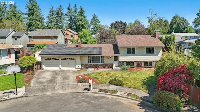 18735 NE Wasco Ct, Portland, OR 97230 - split level home with a chimney, an attached garage, solar panels, concrete driveway, and a residential view