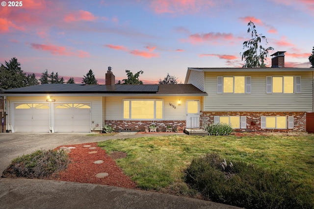 18735 NE Wasco Ct, Portland, OR 97230 - tri-level home with a chimney, brick siding, driveway, a yard, and an attached garage