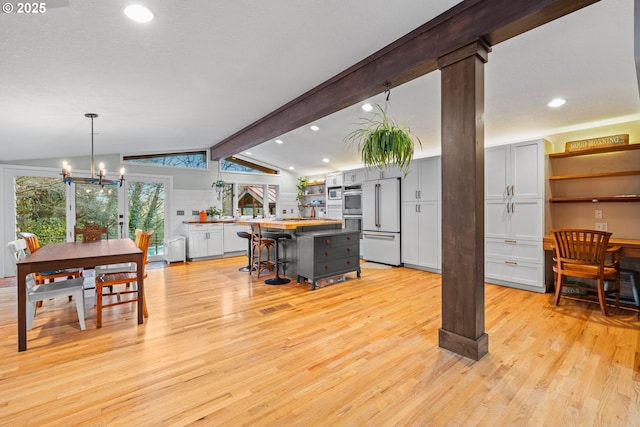 interior space with decorative columns, recessed lighting, lofted ceiling with beams, an inviting chandelier, and light wood-style floors