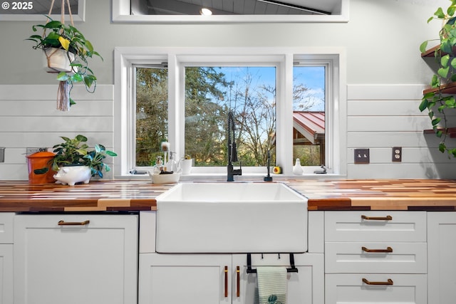 kitchen featuring butcher block countertops, white cabinets, and a sink