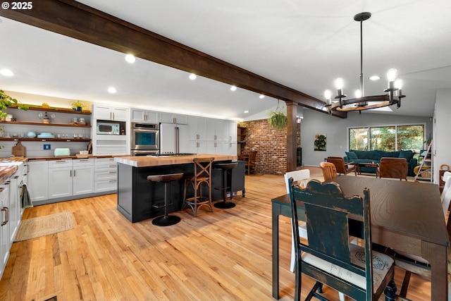 dining room featuring light wood-type flooring, indoor bar, vaulted ceiling with beams, and an inviting chandelier