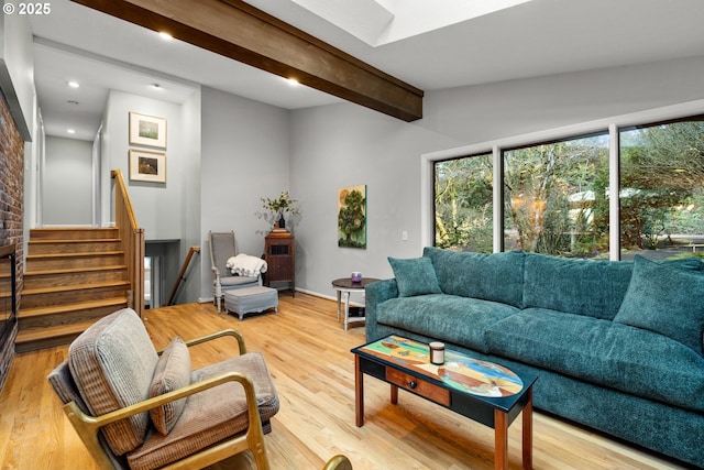 living room featuring a skylight, light wood-style flooring, stairway, beam ceiling, and recessed lighting