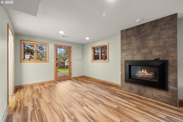 unfurnished living room featuring recessed lighting, visible vents, a tiled fireplace, wood finished floors, and baseboards