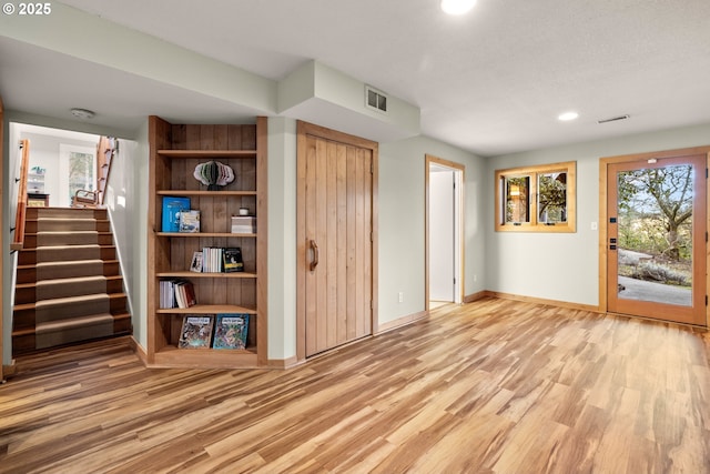 interior space with stairs, wood finished floors, visible vents, and baseboards