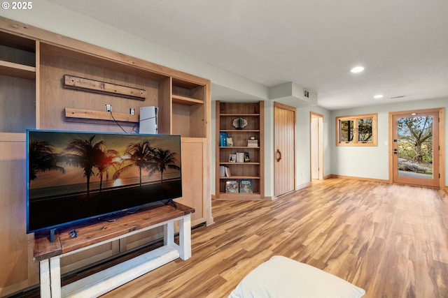 living room featuring built in shelves, baseboards, wood finished floors, and recessed lighting