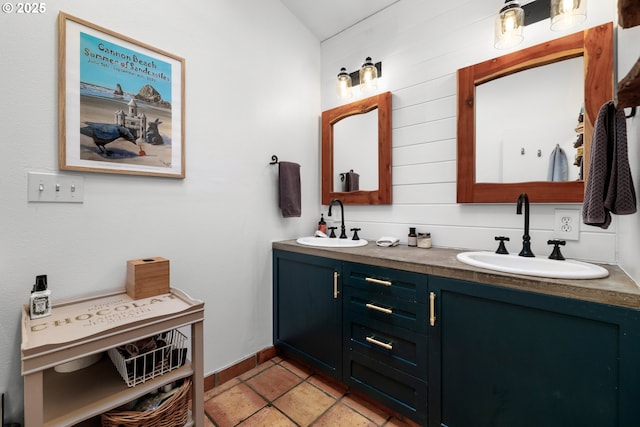 full bath with double vanity, tile patterned flooring, vaulted ceiling, and a sink