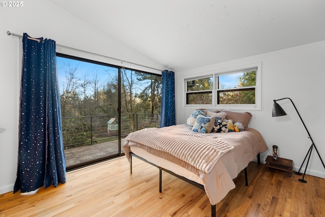 bedroom with access to exterior, vaulted ceiling, and wood finished floors