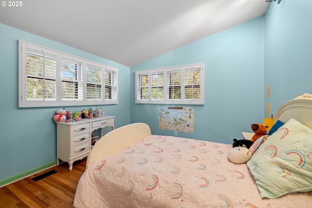 bedroom with visible vents, vaulted ceiling, baseboards, and wood finished floors