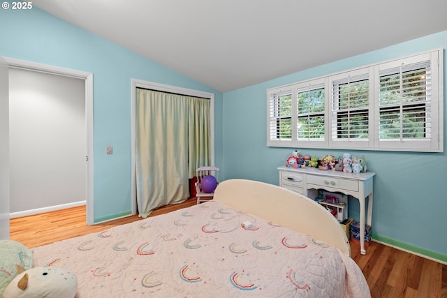 bedroom featuring lofted ceiling, wood finished floors, and baseboards