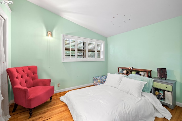 bedroom with baseboards, vaulted ceiling, and wood finished floors