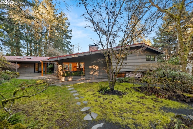 rear view of house with a lawn, a chimney, and a patio