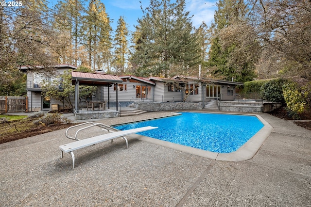 view of swimming pool featuring fence, a diving board, a fenced in pool, and a patio