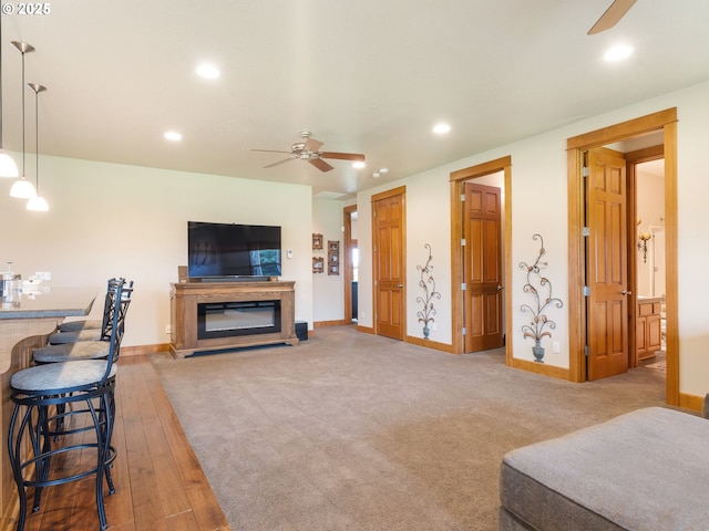 living area featuring recessed lighting, a glass covered fireplace, and ceiling fan
