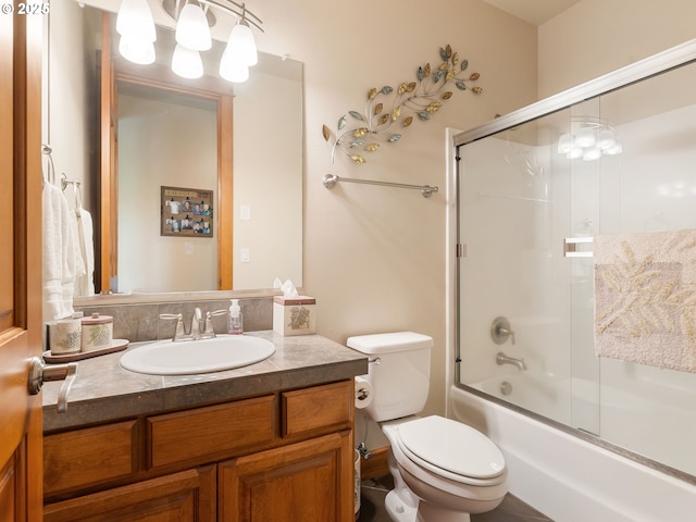 bathroom with toilet, bath / shower combo with glass door, and vanity