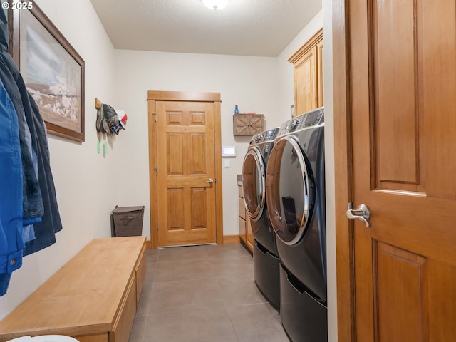 clothes washing area with cabinet space, light tile patterned flooring, and washing machine and dryer