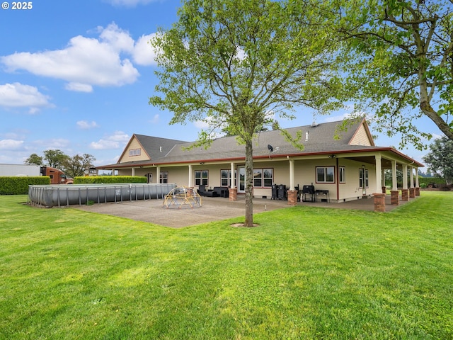 rear view of property with a fenced in pool, a patio, and a lawn
