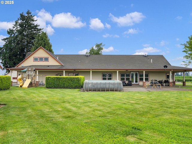 rear view of property featuring a yard, a patio, and an outdoor pool