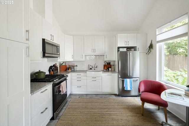 7228 N Villard Ave, Portland, OR 97217 - kitchen featuring appliances with stainless steel finishes, lofted ceiling, backsplash, and white cabinetry