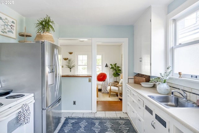 7228 N Villard Ave, Portland, OR 97217 - kitchen featuring healthy amount of natural light, light tile patterned floors, white cabinets, and light countertops