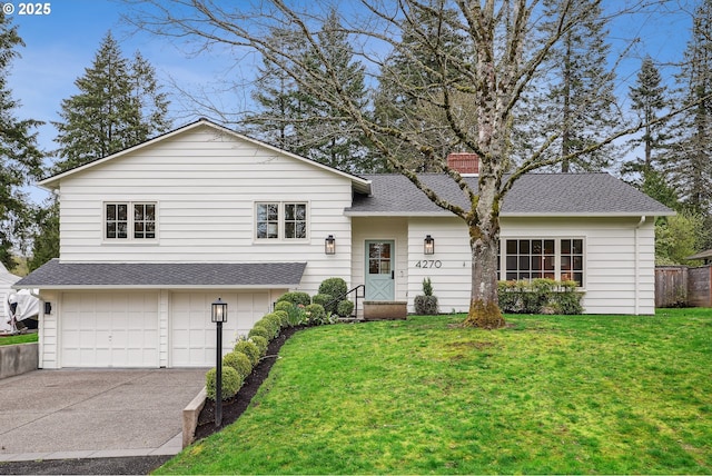 split level home featuring concrete driveway, a garage, a front lawn, and a shingled roof