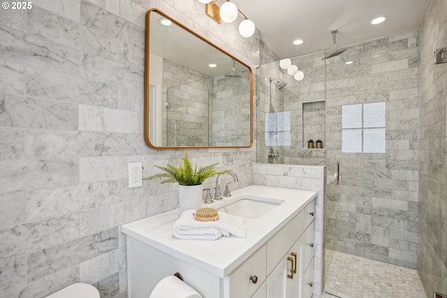 full bath with a stall shower, tile walls, vanity, and recessed lighting