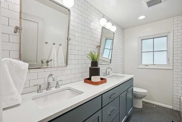 bathroom with tasteful backsplash, toilet, double vanity, tile patterned floors, and baseboards