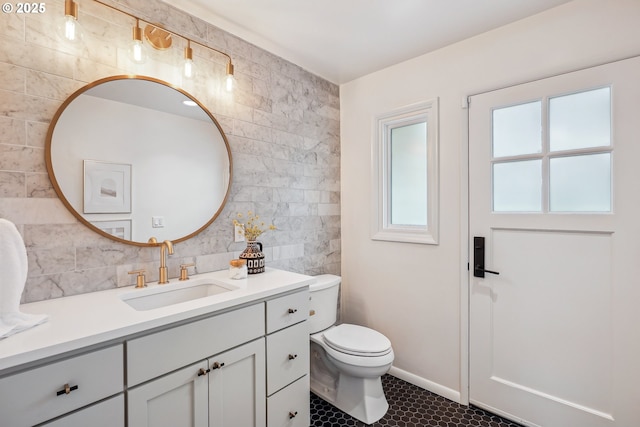 bathroom with tile walls, tile patterned floors, vanity, toilet, and tasteful backsplash