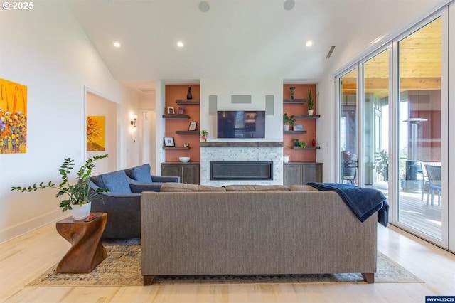 living room with visible vents, light wood-style flooring, recessed lighting, a stone fireplace, and vaulted ceiling