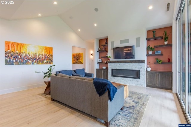 living room featuring a fireplace, light wood-style floors, visible vents, and baseboards