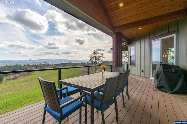 wooden deck featuring outdoor dining area, a yard, a mountain view, and grilling area