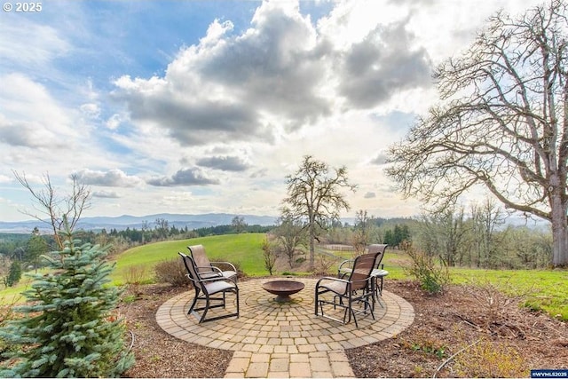 view of patio with a fire pit and a mountain view