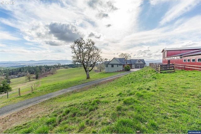 view of yard featuring a mountain view, a rural view, and fence