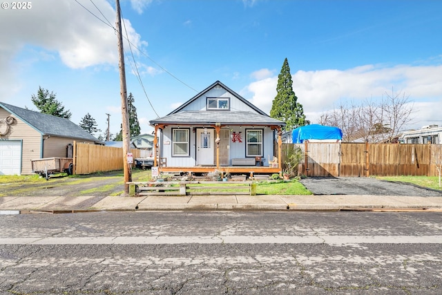 bungalow-style home featuring covered porch and fence