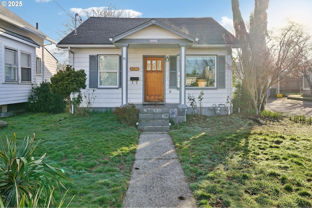 bungalow-style home with a shingled roof and a front yard