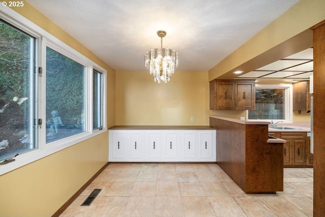 kitchen with hanging light fixtures, a chandelier, sink, and kitchen peninsula