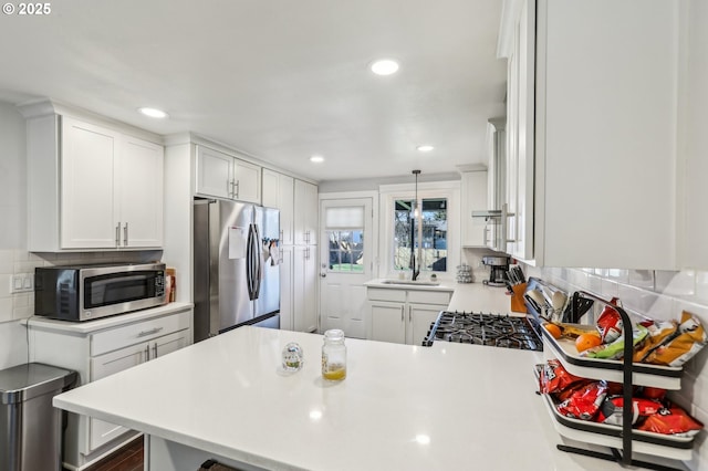 kitchen featuring stainless steel appliances, a peninsula, white cabinets, light countertops, and decorative backsplash