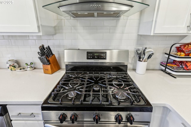 kitchen featuring extractor fan, light countertops, stainless steel gas range, and white cabinetry