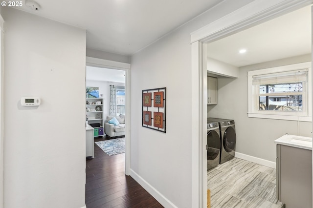 washroom with cabinet space, plenty of natural light, washer and dryer, and wood finished floors