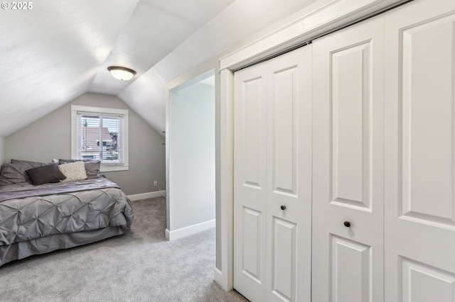 bedroom featuring vaulted ceiling, baseboards, a closet, and light carpet