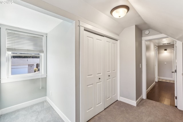 hall with visible vents, baseboards, carpet flooring, and vaulted ceiling