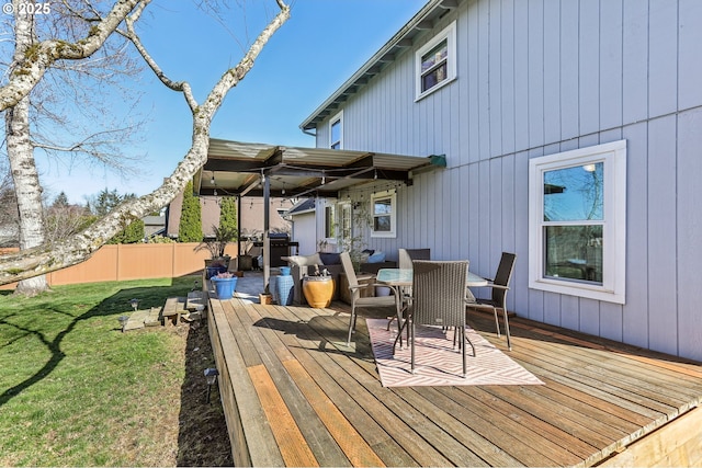 wooden deck featuring outdoor dining area, a yard, and fence