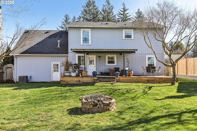 back of house featuring a lawn, fence, an outdoor fire pit, roof with shingles, and central AC unit