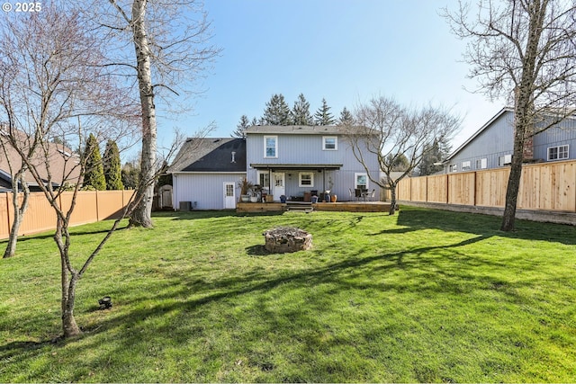 rear view of house featuring a yard, a deck, a fire pit, and a fenced backyard