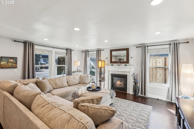 living area with plenty of natural light, recessed lighting, dark wood-type flooring, and a glass covered fireplace