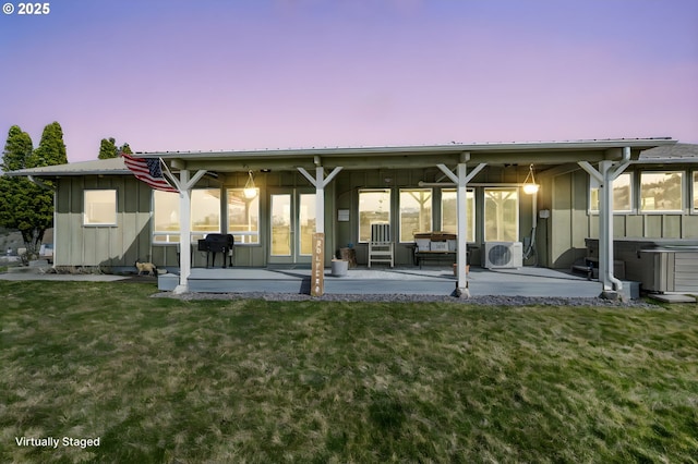 back of house with a patio area, board and batten siding, metal roof, and a yard