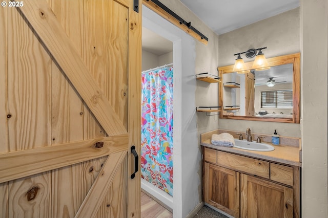 bathroom with curtained shower, wood finished floors, vanity, and baseboards